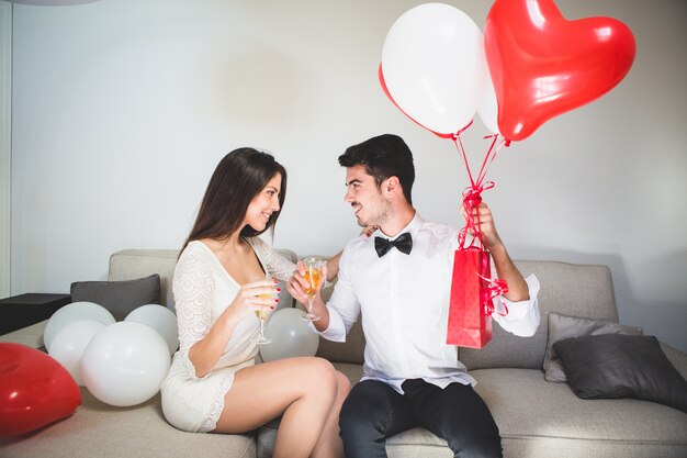 Hombre con regalos tomando una copa con su mujer