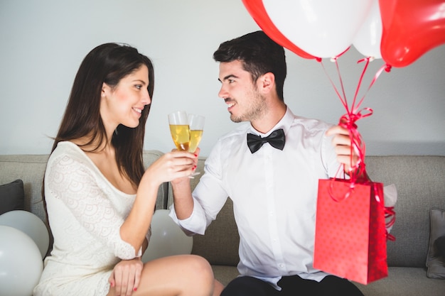 Hombre con regalos tomando una copa con su mujer