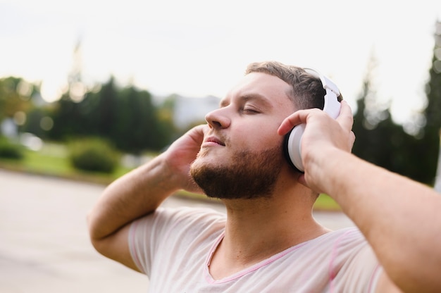 Hombre relajado que sostiene los auriculares con las manos