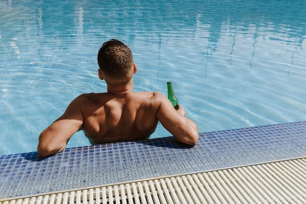 Hombre  relajando al lado de piscina