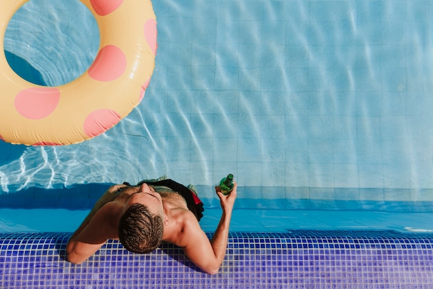 Hombre  relajando al lado de piscina