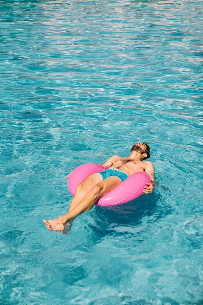 Hombre relajando en anillo flotador en piscina