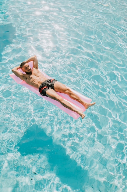 Hombre relajando en flotador en la piscina
