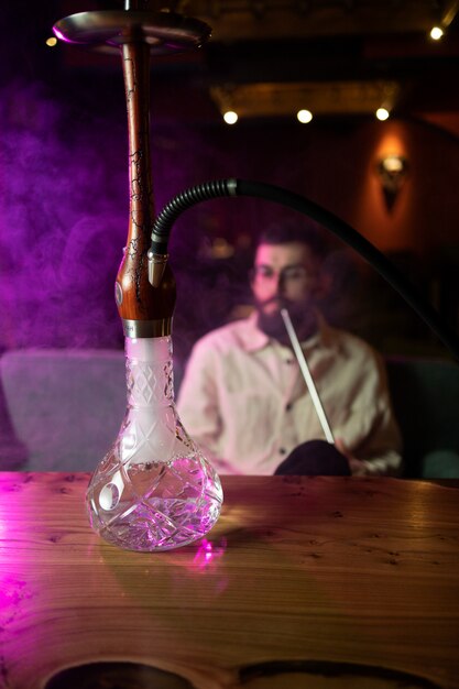 Hombre relajándose vaping de una pipa de agua en un bar.