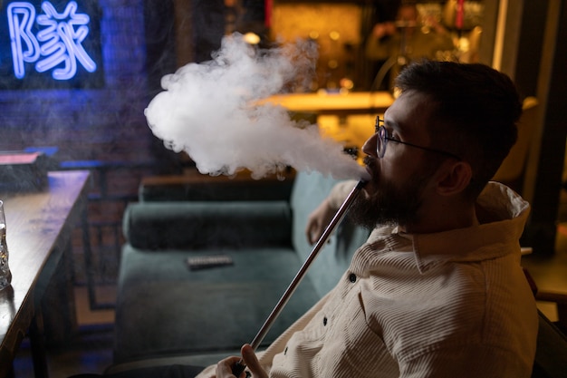 Hombre relajándose vaping de una pipa de agua en un bar.