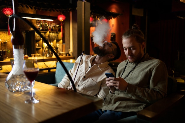 Hombre relajándose vaping de una pipa de agua en un bar.