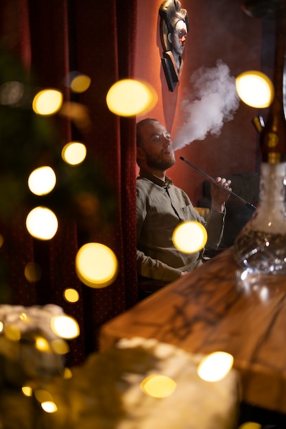 Hombre relajándose vaping de una pipa de agua en un bar.
