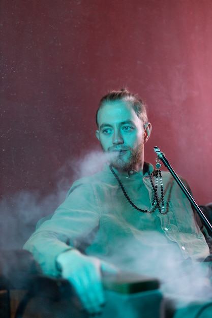 Hombre relajándose vaping de una pipa de agua en un bar.