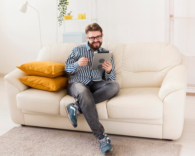 Hombre relajante en casa en el sofá con tableta