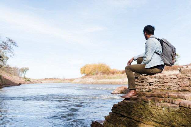 Hombre relajante cerca de la vista lateral de agua