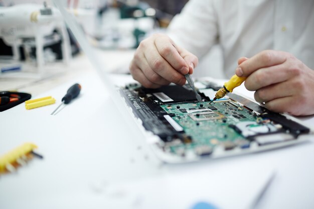 Hombre reparando la placa de circuito en la computadora portátil