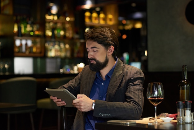 Hombre en restaurante leyendo noticias en línea