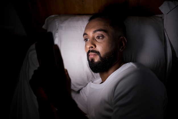 Hombre revisando su teléfono antes de dormir