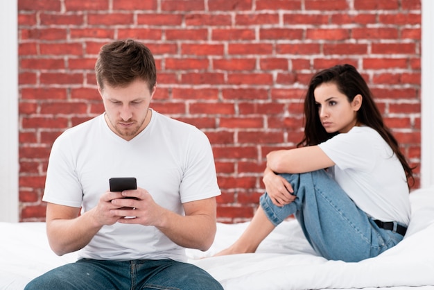 Hombre revisando su teléfono mientras su novia está enojada