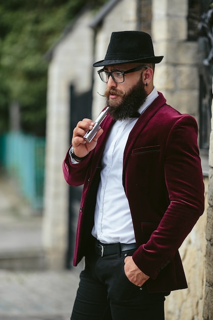 Un hombre rico con barba fuma cigarrillo electrónico.