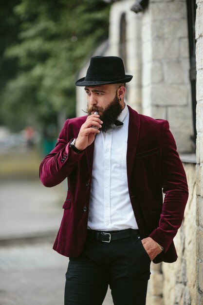 Un hombre rico con barba fuma cigarrillo electrónico.