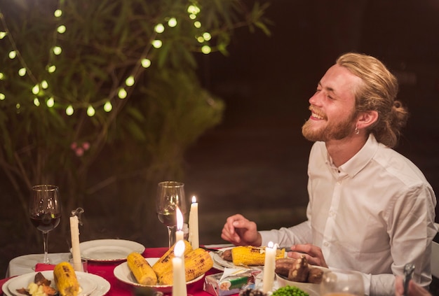 Hombre riendo mientras está sentado en la mesa festiva