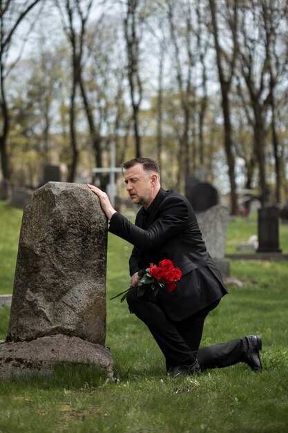 Hombre rindiendo respeto a una lápida en el cementerio