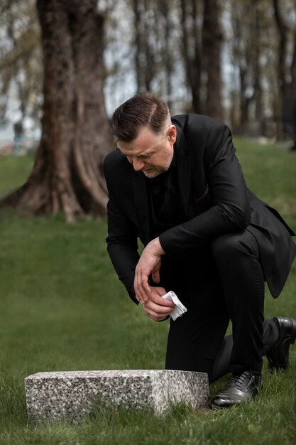 Hombre rindiendo respeto a una lápida en el cementerio