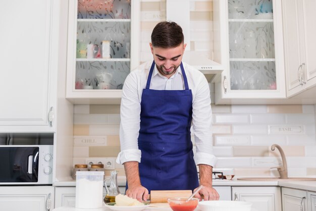 Hombre rodando masa para pizza en la cocina