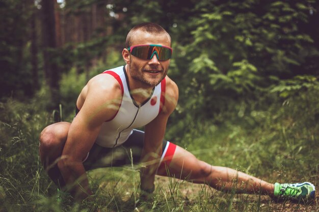 Hombre en ropa deportiva haciendo extensión corporal en el bosque.