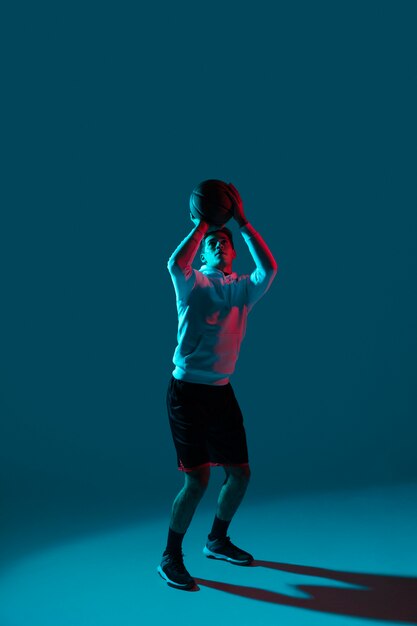 Hombre en ropa deportiva jugando baloncesto con luces frías