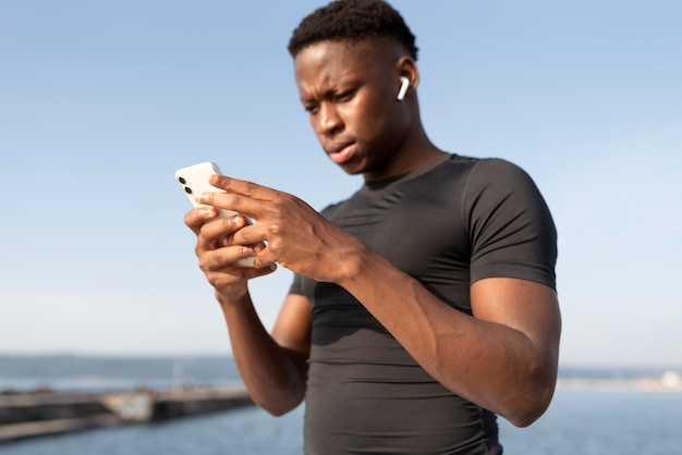 Hombre en ropa deportiva sosteniendo su smartphone
