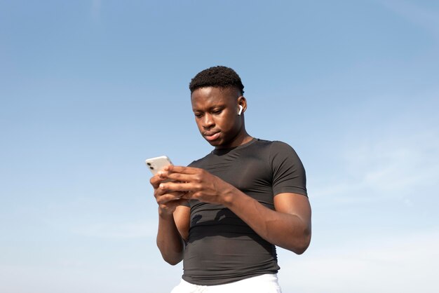 Hombre en ropa deportiva sosteniendo su smartphone