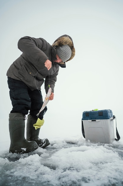 Hombre en ropa de invierno pescando solo afuera