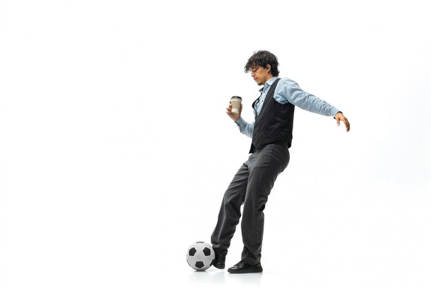 Hombre en ropa de oficina jugando al fútbol o fútbol con pelota en el espacio en blanco. Aspecto inusual para empresario en movimiento, acción. Deporte, estilo de vida saludable.