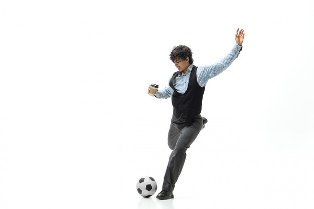 Hombre en ropa de oficina jugando al fútbol o fútbol con pelota en el espacio en blanco. Aspecto inusual para empresario en movimiento, acción. Deporte, estilo de vida saludable.