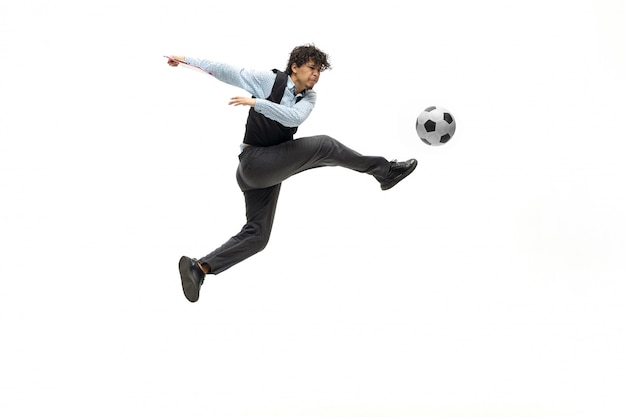 Hombre en ropa de oficina jugando al fútbol o fútbol con pelota en el espacio en blanco. Aspecto inusual para empresario en movimiento, acción. Deporte, estilo de vida saludable.