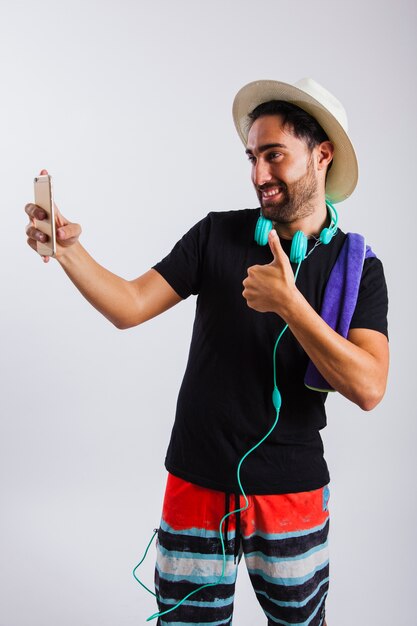 Hombre en ropa de verano haciendo un selfie y el signo de ok