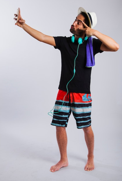 Hombre en ropa de verano haciendo un selfie y el signo de la victoria