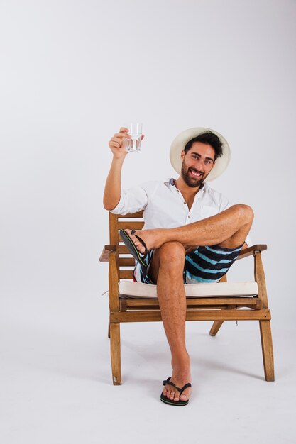 Hombre en ropa de verano levantando un vaso de agua