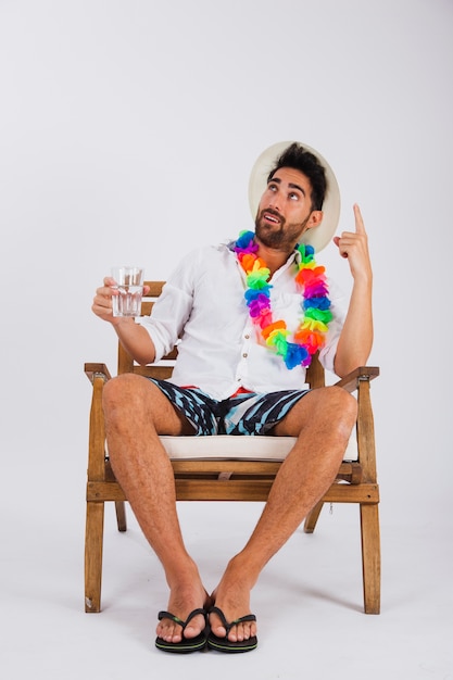 Hombre en ropa de verano con vaso de agua apuntando hacia en cielo