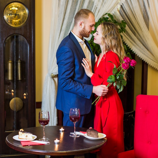 Foto gratuita hombre con rosas abrazando a una mujer bonita en restaurante