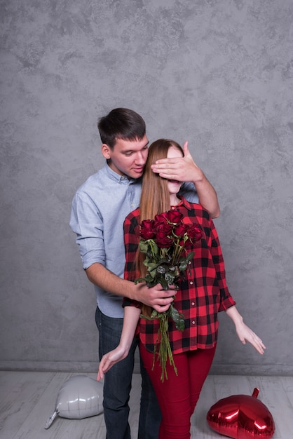 Foto gratuita hombre con rosas cubriendo ojos de mujer