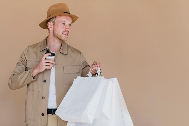 Hombre rubio con bolsas de compras y café