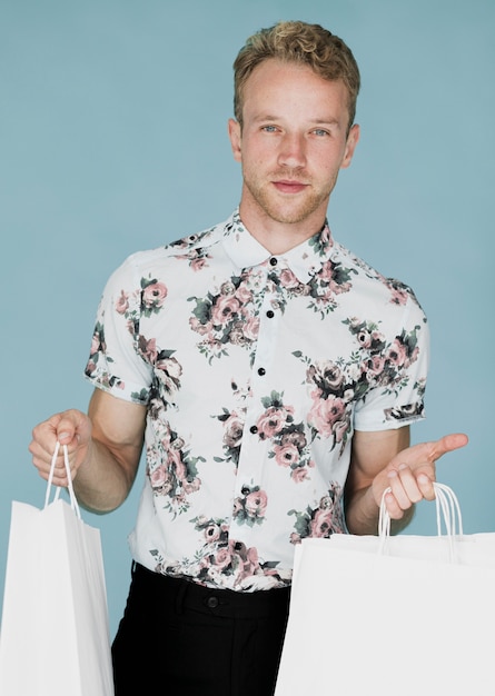 Hombre rubio en camisa con bolsas de compras en ambas manos