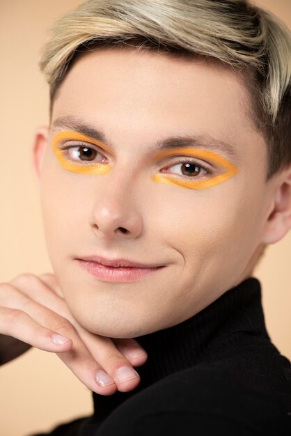 Hombre rubio sonriente con delineador de ojos naranja