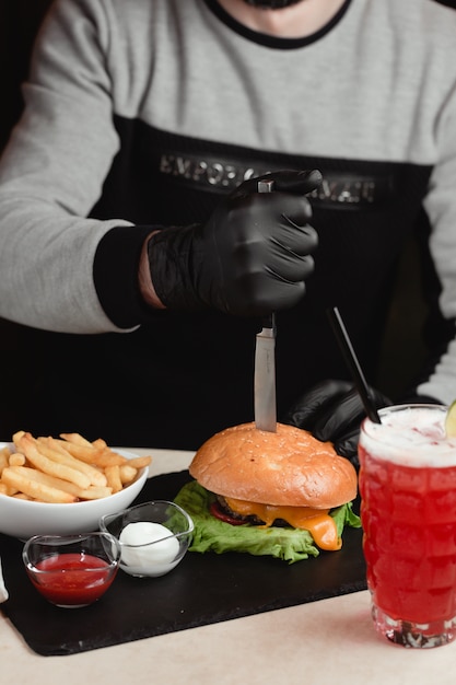 Foto gratuita hombre sacando un cuchillo de la hamburguesa.