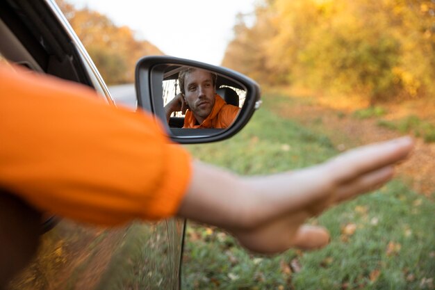Hombre sacando la mano del coche durante un viaje por carretera