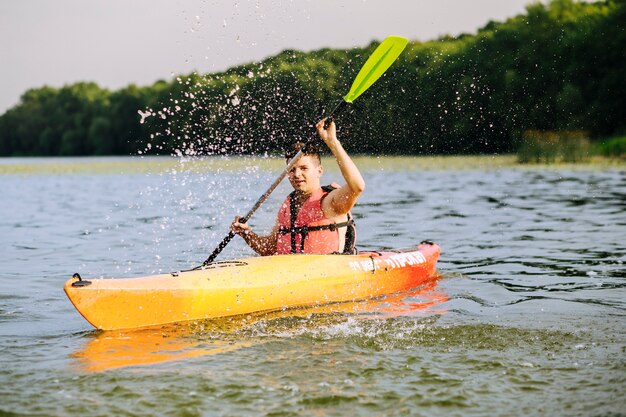 Hombre salpicaduras de agua con paleta mientras kayak en el lago