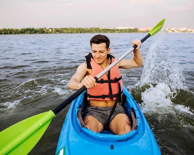 Hombre salpicaduras de agua con paleta mientras kayak en el lago