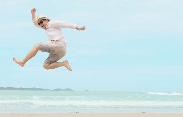 El hombre salta feliz durante las vacaciones en la playa del mar de Tailandia