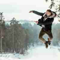 Foto gratuita hombre saltando al aire libre en la naturaleza durante el invierno y apuntando al espacio de la copia