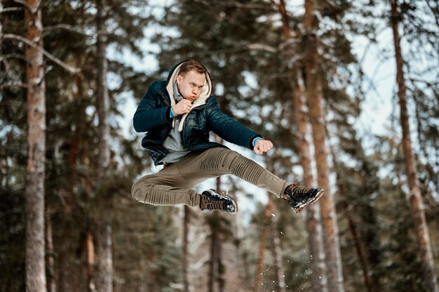 Hombre saltando al aire libre en la naturaleza durante el invierno