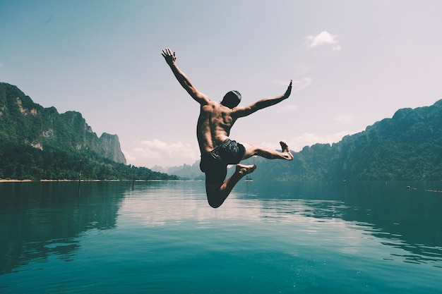 Hombre saltando de alegría por un lago