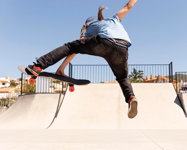 Hombre saltando alto con patineta full shot